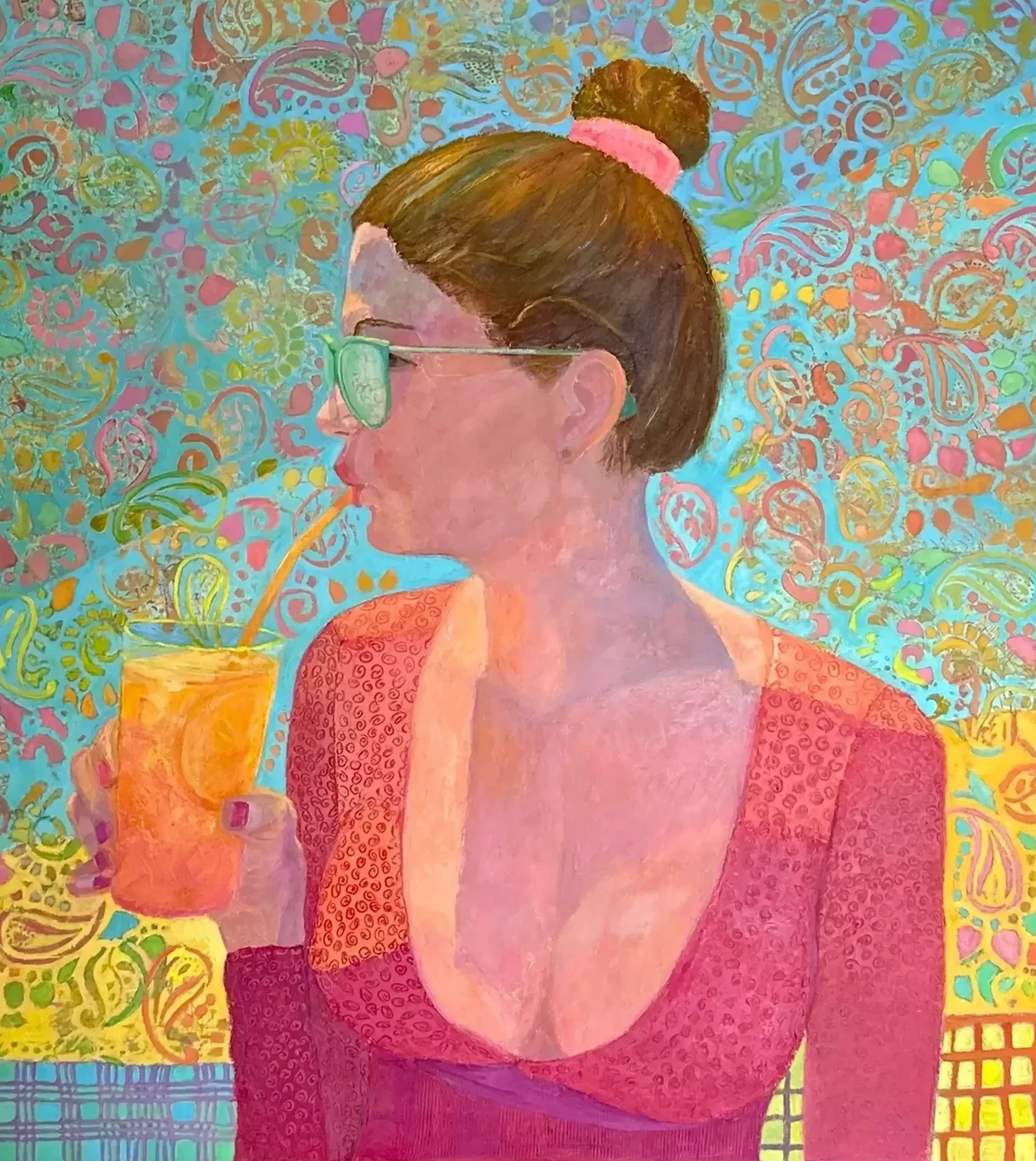 Woman sipping drink against colorful patterned background.